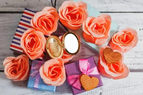 Opened blank locket surrounded by roses and gifts Stock Photos