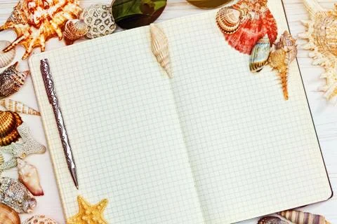 Opened blank notebook surrounded by sea shells Stock Photos