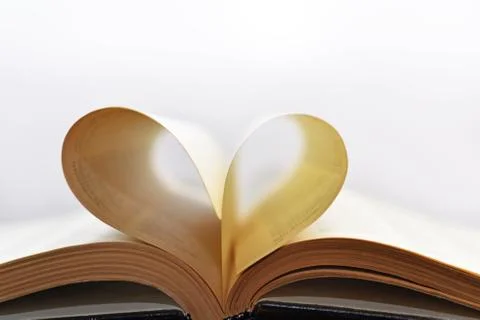 Opened book with heart form sheets. Stock Photos