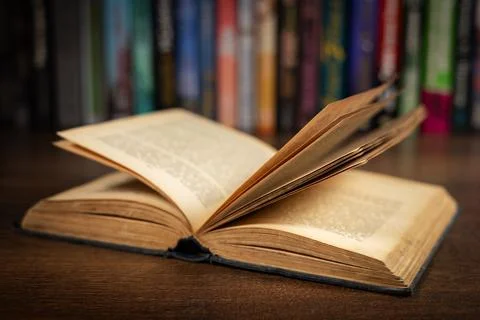 Opened book, lying on the bookshelf in library Stock-Fotos