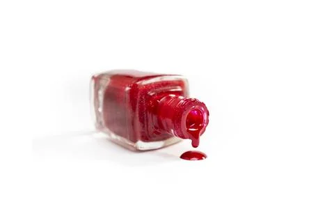 Opened bottle with bright red nail polish spilling isolated on white Stock Photos