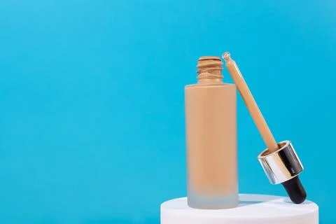 Opened Bottle with foundation liquid beige cream on stand, white podium. Pr.. Stock Photos