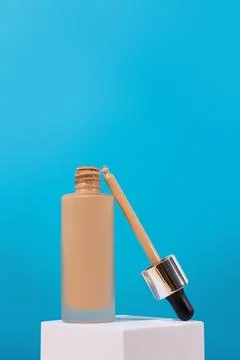 Opened Bottle with foundation liquid beige cream on stand, white podium. Pr.. Stock Photos