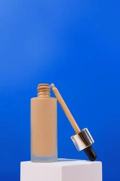 Opened Bottle with foundation liquid beige cream on stand, white podium. Pr.. Foto stock