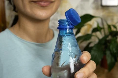 Opened bottle with stationary plastic cap and young woman in background Stock Photos