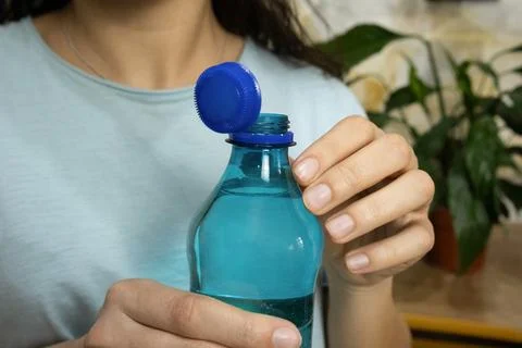 Opened bottle with stationary plastic cap and young woman in background Stock Photos
