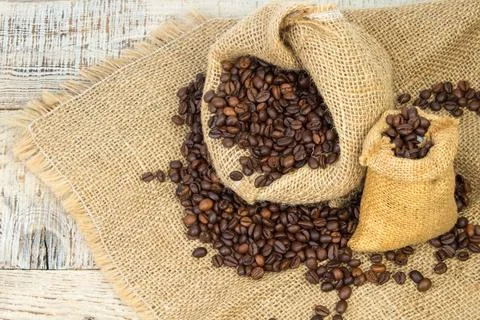 Opened burlap bags, a cup of coffee, scattered whole coffee beans on a whit.. 写真素材