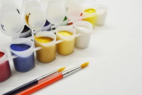 Opened cans with different paints and two brushes on a white background Stock Photos