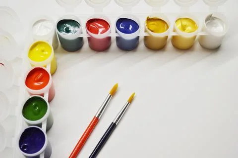 Opened cans with different paints and two brushes on a white background Stock Photos
