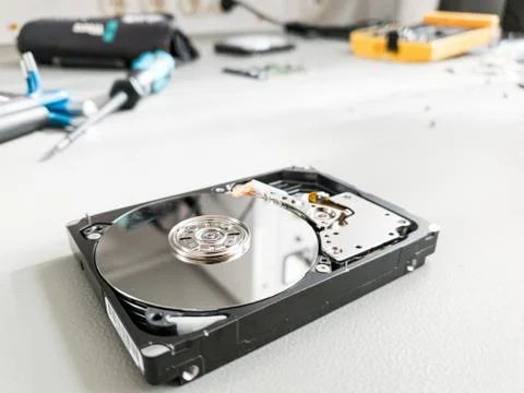 Opened computer hard drive on a table prepared to be fixed. Stock Photos