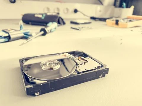 Opened computer hard drive on a table prepared to be fixed. Stock Photos