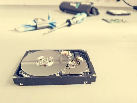 Opened computer hard drive on a table prepared to be fixed. Stock Photos