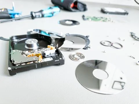 Opened computer hard drive on a table prepared to be fixed. Stock Photos