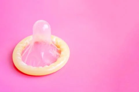 Opened condom close up on pink background with copy space - childfree and sex Stock Photos