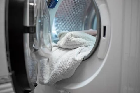 Opened dryer machine full of white clothes. Closeup. Front view. Foto stock