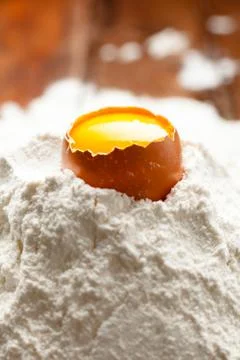 Opened Egg Shell with Yolk on Flour Stock Photos