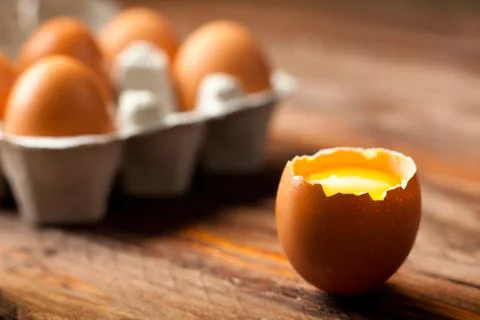 Opened Egg Shell with Yolk on Wood Stock Photos