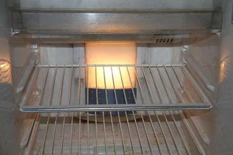 An opened empty refrigerator with a central light source. Stock Photos