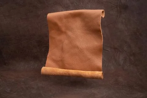 Opened genuine leather scroll levitating on brown vignette  background, abs.. Stock Photos
