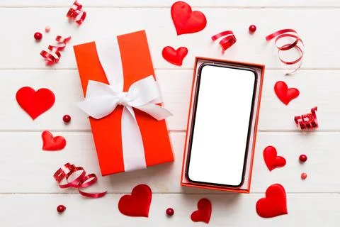 Opened gift box with ribbon and phone on color background, top view. Blank op Stock Photos