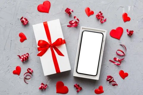 Opened gift box with ribbon and phone on color background, top view. Blank op Stock Photos