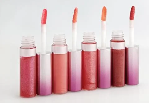 Opened gloss for lips set with color brushes on white, arranged in line persp Foto stock