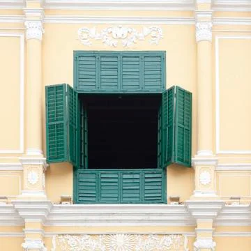 The opened green window on the yellow wall Stock Photos