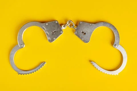 Opened handcuffs on yellow background. Stock Photos