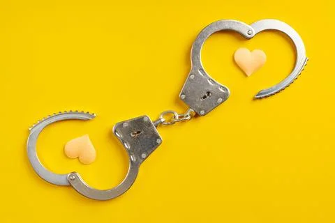 Opened handcuffs on yellow background. Stock Photos