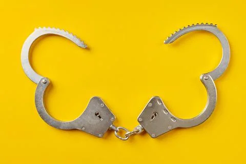 Opened handcuffs on yellow background. Stock Photos