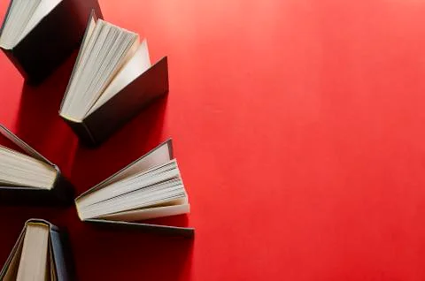 Opened hardback books on a red background. Foto stock
