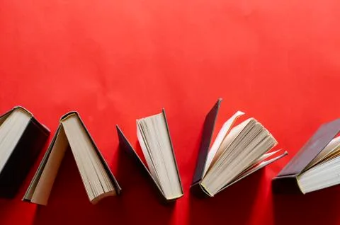 Opened hardback books on a red background. Stock Photos