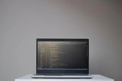 Opened laptop with code on the screen on the table Stock Photos