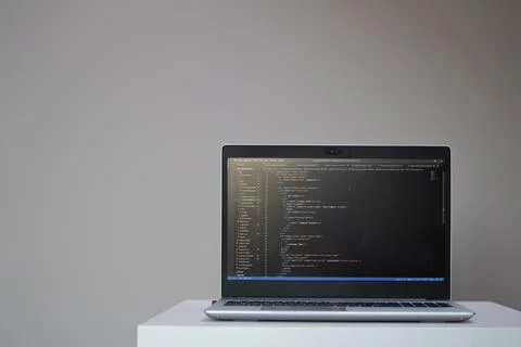 Opened laptop with code on the screen on the table Stock Photos