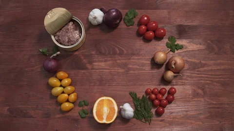 Opened Meat tin can served with vegetables and fruits, top view of a wooden Stock Footage 128299377