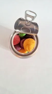 Opened metal pull-tab can containing colorful cookies on a white background Stock Photos