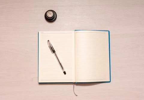 Opened notebook with black pen and official stamp on a white wooden table, to Stock Photos