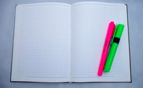 Opened notebook with clear squared paper and pink and green markers 库存照片