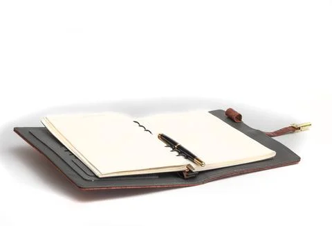 Opened notebook with a pen on a page on a white background. Stock Photos