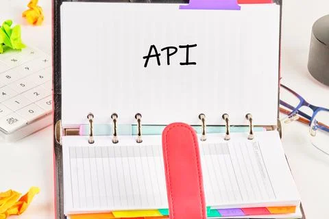 An opened notebook reveals an API section marked with colorful tabs. Office.. Stock Photos