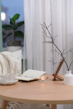 Opened notebook with white pen, a cup of tea and burning candle on wooden table Stock Photos