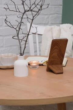 Opened notebook with white pen, a cup of tea, burning candle, vase with branches Stock Photos