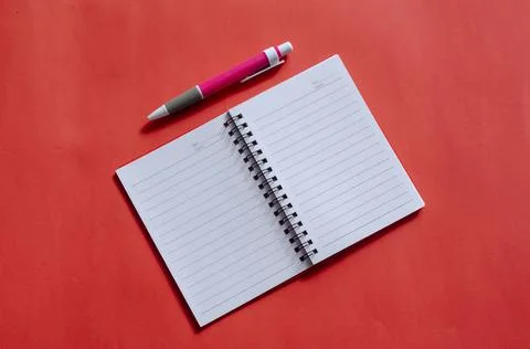 Opened notepad and pink pen on a red background. Spring notepad with blank wh Stock Photos
