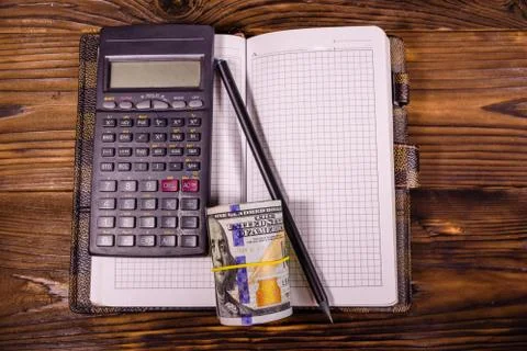 Opened notepad, one hundred dollar banknotes, scientific calculator Stock Photos