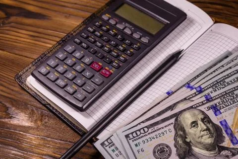 Opened notepad, one hundred dollar banknotes, scientific calculator Stock Photos