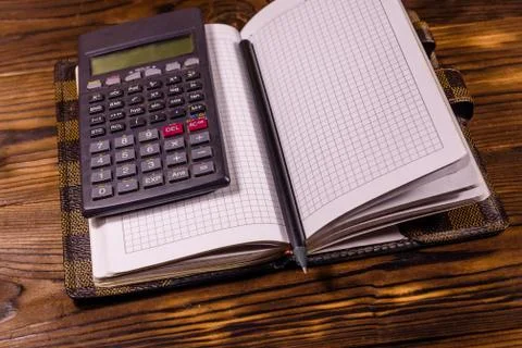 Opened notepad, scientific calculator and pencil on wooden table Stock Photos