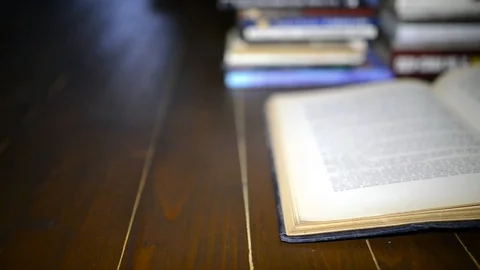 Opened old book on the floor, books in rows on the blured background Stock Footage 98809081
