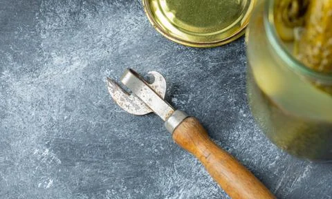Opened pickle jar and jar opener on grey background Stock Photos