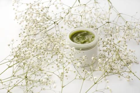 Opened plastic container with cream and flowers on a white background. face.. Stock-Fotos