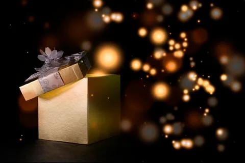 Opened present box with golden dots in the dark on the background 库存照片